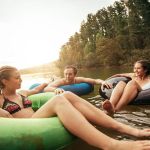 Portrait of young friends floating on lake with inflatable rings. Young people relaxing in water on a summer day. Enjoying their holidays at the lake.